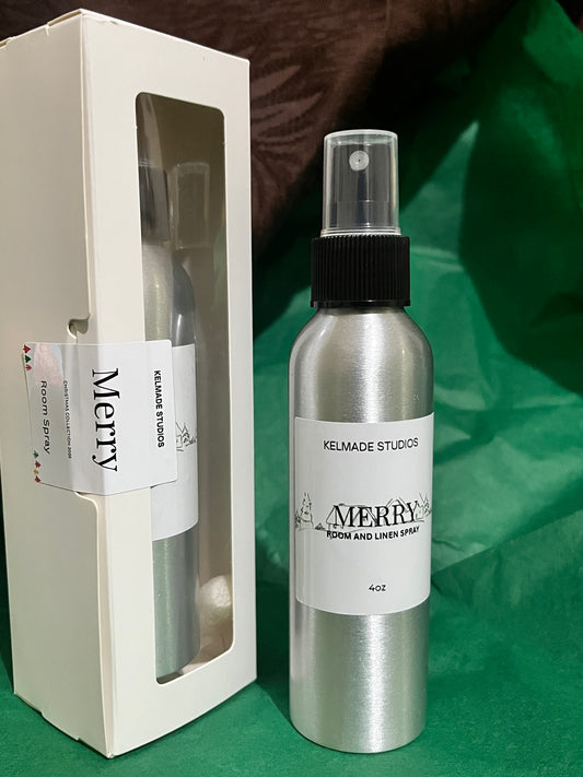 Silver room spray bottle with 'Merry' label on a green surface